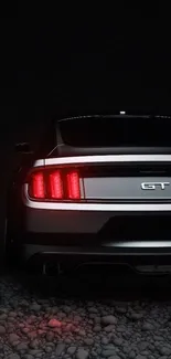 Rear view of a sleek GT car in dim lighting on rocky ground.