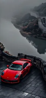 Red sports car on historic wall in mist.
