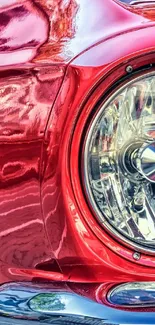 Close-up of a red vintage car's gleaming headlight.