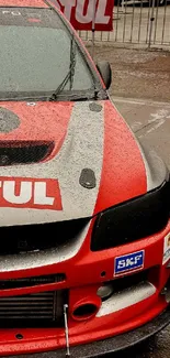 Red racing car with wet glossy finish against a blurred background.