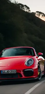 Red sports car driving on a scenic winding road at dusk.