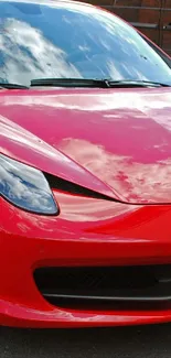 Sleek red sports car parked on a street, reflecting a clear sky.