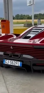 Sleek red supercar parked at a gas station.