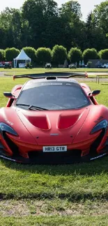 Sleek red supercar on green grass, perfect for mobile wallpaper.