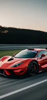 Sleek red supercar on racetrack at sunset.