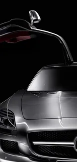 Sleek silver car with gullwing door open against a dark background.