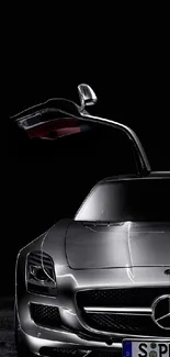 Sleek silver luxury car with open wing door against a black background.