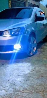 Sleek silver car with blue headlights in urban evening setting.