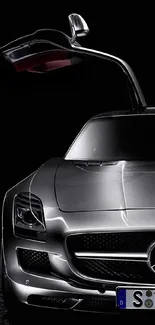 Sleek silver luxury car with open gullwing door on a black background.