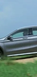 Silver car driving on a scenic road with green grass and blue sky.