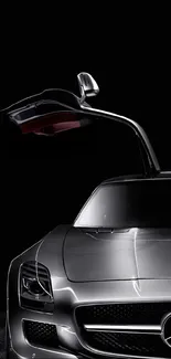 Sleek silver car with gullwing door on a black background.