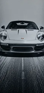 Front view of a sleek silver luxury car on a road in grayscale tones.