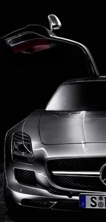 Sleek silver sports car with gullwing door open against dark background.