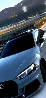 Silver sports car with mountain backdrop.