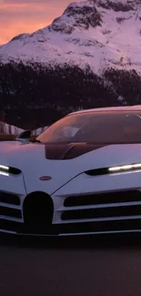 Luxury sports car with snowy mountains at sunset.