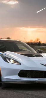 Sleek white sports car under an orange sunset sky.