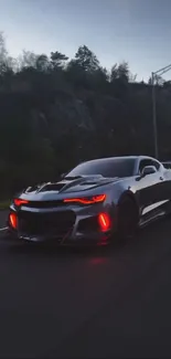 Sleek sports car driving at night on open road.