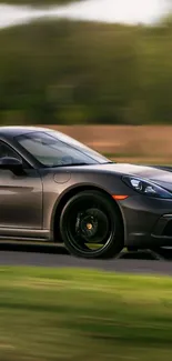 Sleek sports car driving on a scenic road with a blurred green background.