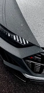 Gray sports car with raindrops, close-up view.