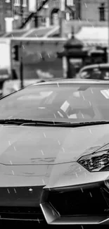 Black and white wallpaper of a sports car in the rain with urban background.