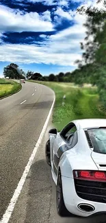 Sleek white sports car on a winding open road under a blue sky.