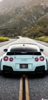 Sports car on a scenic open road with mountainous background.