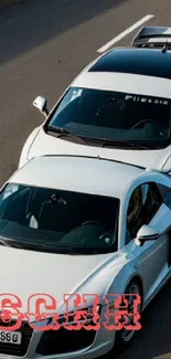 Two sleek white sports cars on road.