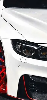 Sleek white sports car with red rims on a dark background.