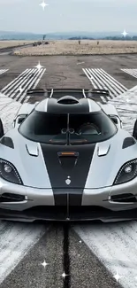 Sleek sports car on a runway with open doors and dramatic design.