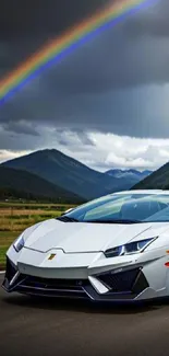 Sleek sports car under a vibrant rainbow with mountain backdrop.