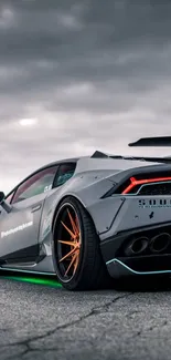 Sleek sports car on open road with cloudy sky background.