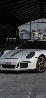 White sports car in a dimly lit warehouse setting.