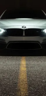 Elegant gray sports car with glowing headlights in the dark.