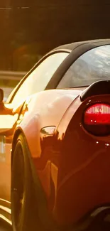 Orange sports car in motion with sunlight reflection.