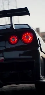 Sleek black sports car with red tail lights.