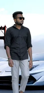 Man in sunglasses posing with a sleek car in front of a famous bridge under a clear sky.