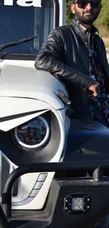 Man in leather jacket leaning on a rugged SUV near a river.