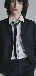 Person in a nicely fitted black suit with a white shirt and loose tie.