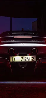 Sleek supercar rear view at night with glowing red taillights.