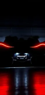 Supercar with glowing red taillights against a black backdrop at night.