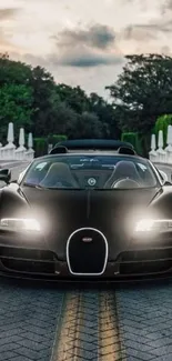 Luxurious black supercar on a scenic road at sunset.