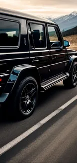 Black SUV on a scenic mountain road with stunning background.