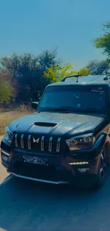 Black SUV on scenic road under blue sky.