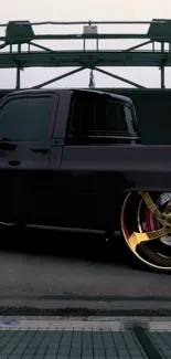 Sleek black truck with eye-catching golden rims on an urban street.