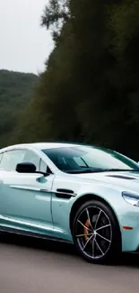 Turquoise sports car on a scenic road, conveying speed and elegance.