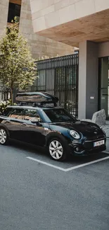 Black Mini car parked against modern building in city.