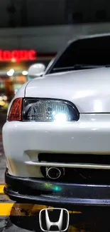 Sleek white car parked in a vibrant urban night scene.