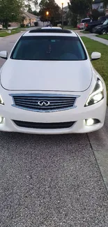 Sleek white car on a suburban street, front view.