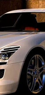 Sleek white sports car with shiny rims on a stone backdrop.