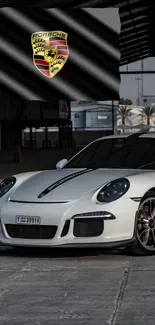 Sleek white Porsche in an industrial setting with logo backdrop.